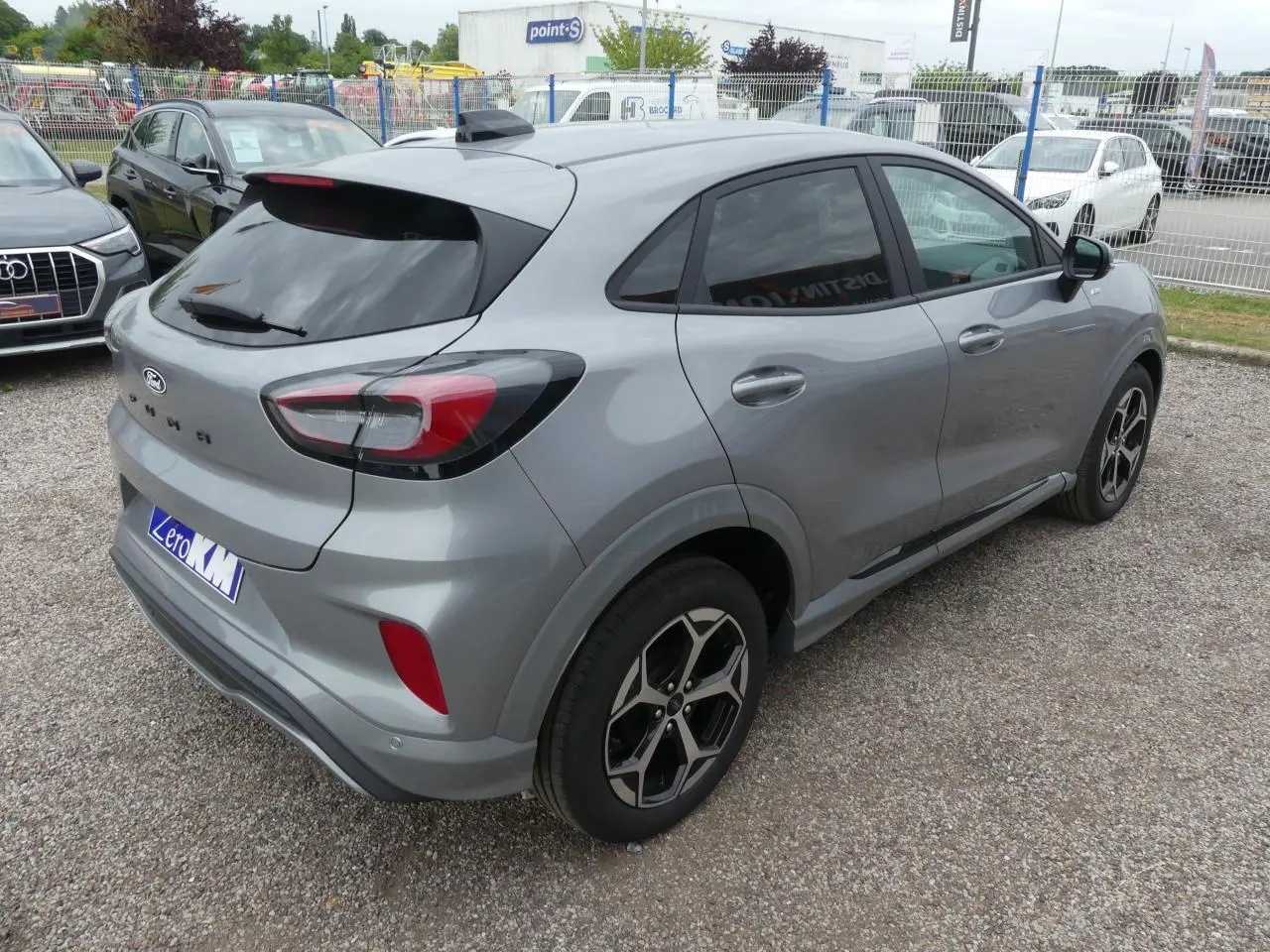 Vue 3/4 arrière droite d'un Ford Puma gris métallisé 2025 avec jantes alliage et vitres surteintées.