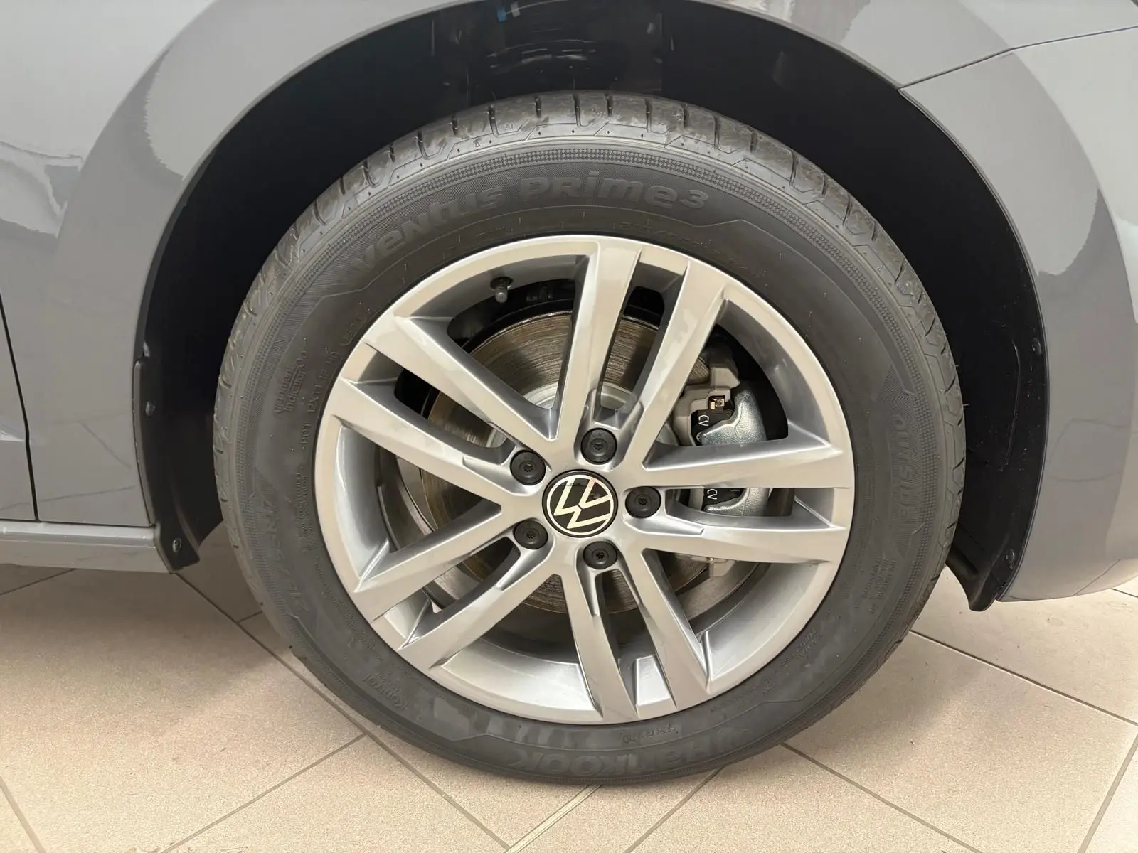 Gros plan sur la roue avant gauche gris dauphin du Volkswagen Touran 2025 avec jante alliage 17 pouces et logo VW central.