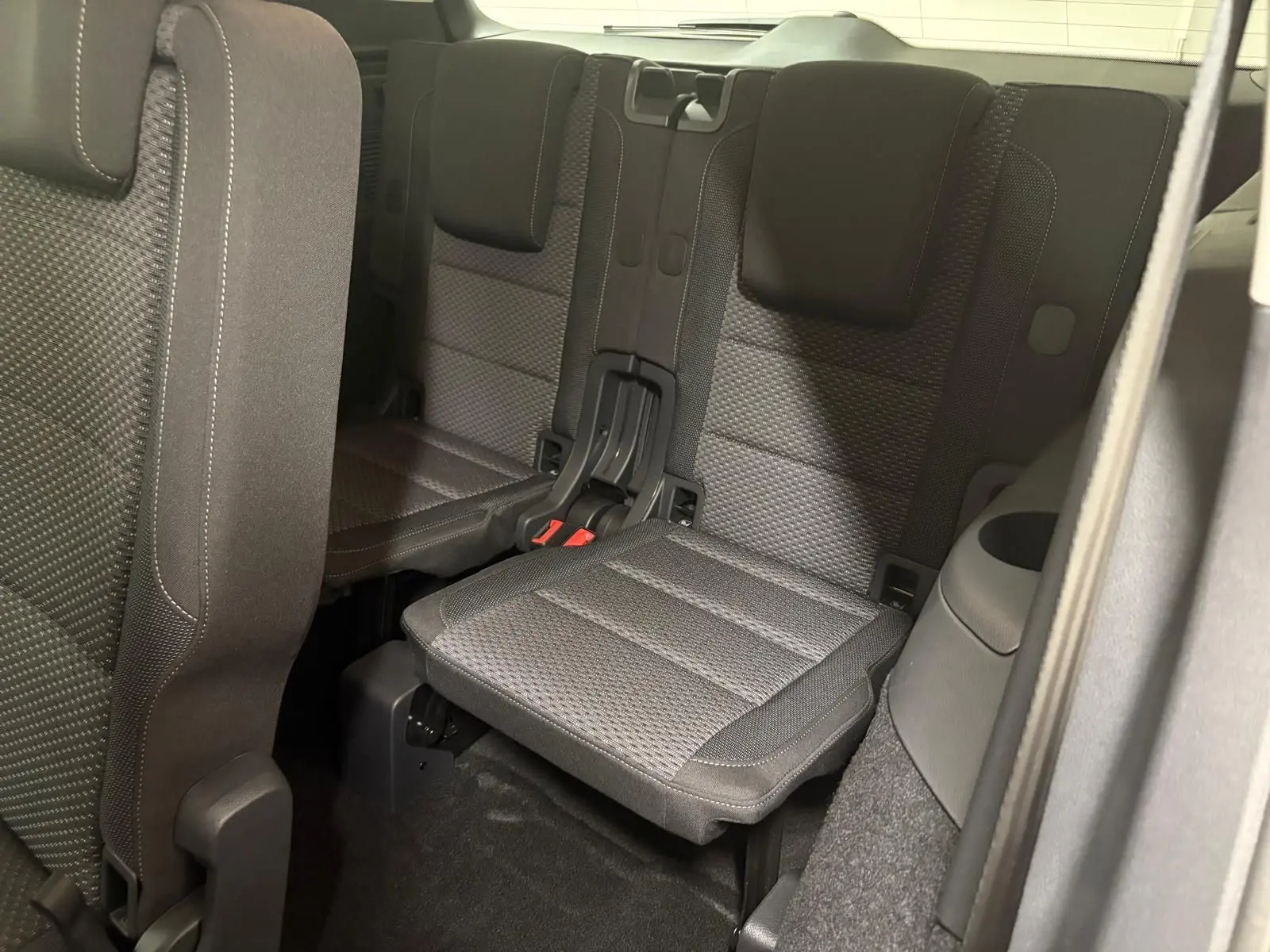Vue intérieure sur la troisième rangée de sièges en tissu gris foncé du Volkswagen Touran 2025, version 7 places.
