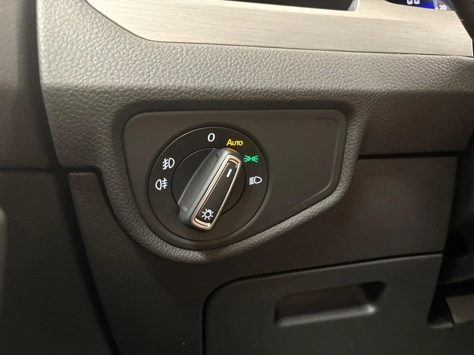 Gros plan sur le bouton de commande des phares du Volkswagen Touran gris dauphin, intérieur côté conducteur.