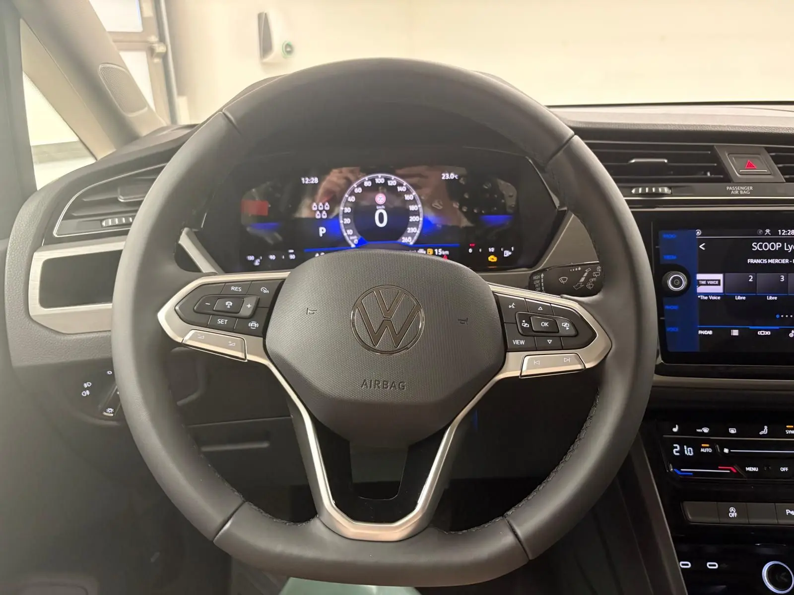 Vue rapprochée du volant noir du Volkswagen Touran 2025 gris dauphin avec commandes intégrées et tableau de bord digital.