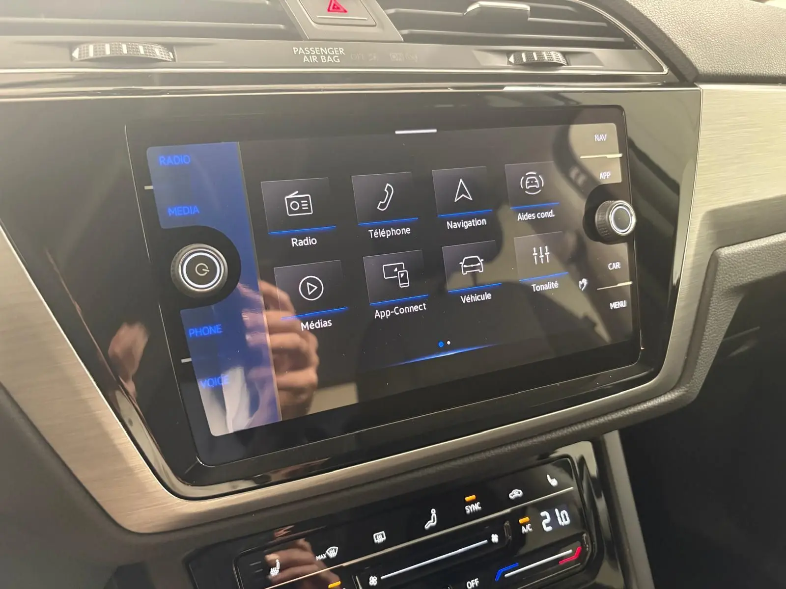 Écran tactile central du tableau de bord du Volkswagen Touran 2025, affichant les options multimédia et aides à la conduite.