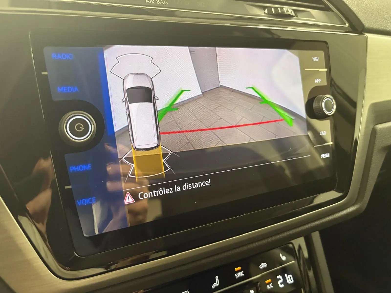 Écran tactile du système multimédia montrant la caméra de recul avec guidage de trajectoire du Volkswagen Touran gris Dauphin.