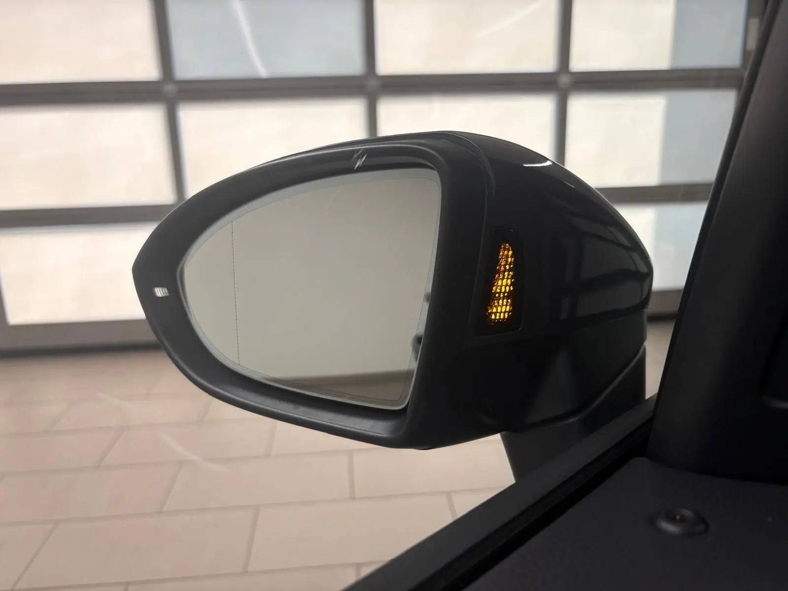 Rétroviseur extérieur côté droit du Volkswagen Touran gris Dauphin 2025 avec clignotant orange allumé.