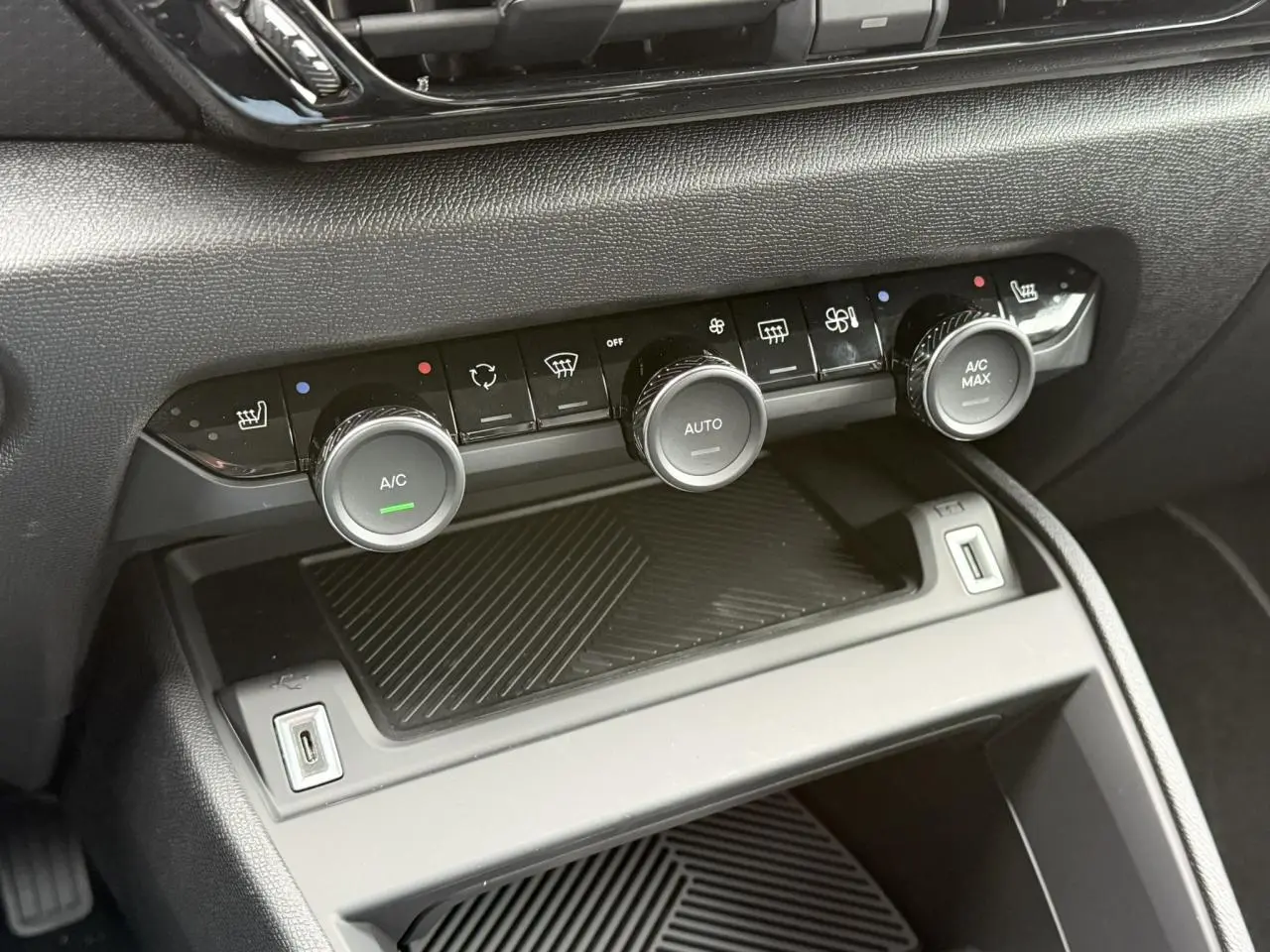 Gros plan sur la console centrale noire de la Citroën C4 avec commandes climatisation et ports USB visibles