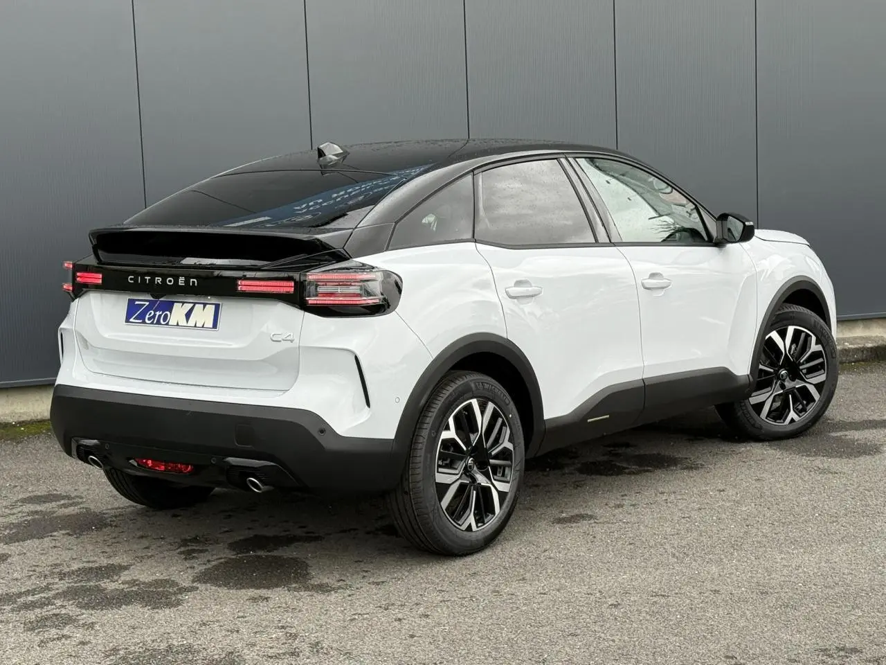 Vue 3/4 arrière droite d'une Citroën C4 hybride blanche avec toit noir et jantes alliage 18 pouces.