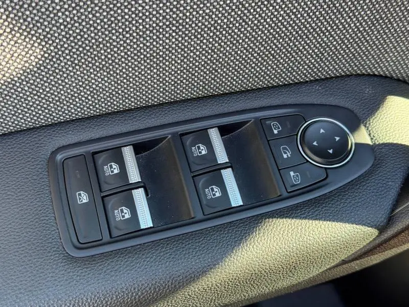 Gros plan sur les commandes des vitres électriques et rétroviseurs côté conducteur du Renault Captur 2025 Rouge Flamme.