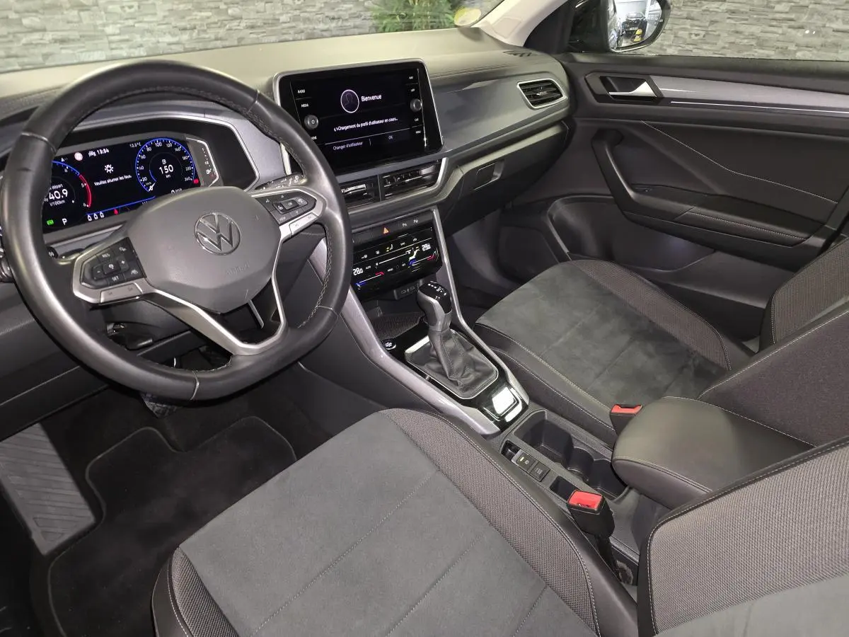 Intérieur noir du Volkswagen T-Roc 2022 vu côté conducteur, avec tableau de bord digital et écran tactile central.