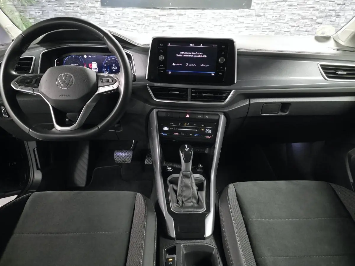Vue intérieure avant du Volkswagen T-Roc 2022 noir, avec tableau de bord digital et écran tactile central.
