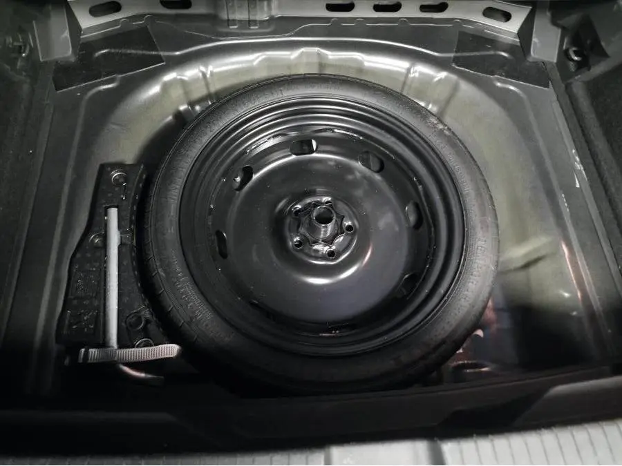 Vue plongeante sur la roue de secours compacte noire dans le coffre du Volkswagen T-Roc 2.0 TDI 2022.