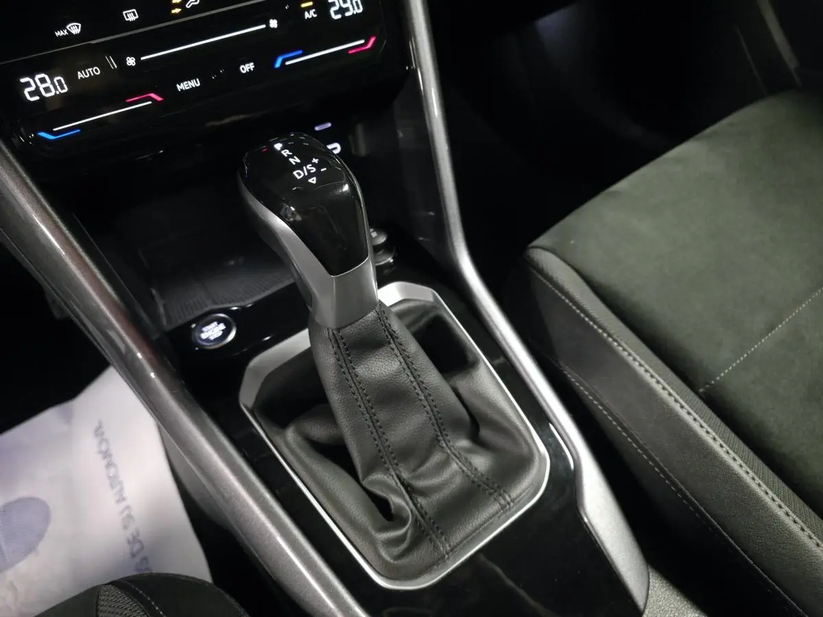 Gros plan sur la console centrale du Volkswagen T-Roc 2022, levier de vitesse automatique noir et sellerie Artvelours.