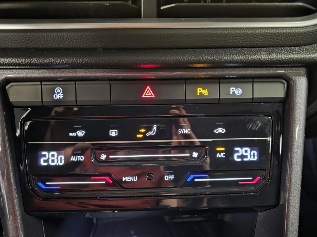 Gros plan sur la console centrale noire du Volkswagen T-Roc 2022, affichant la climatisation bi-zone réglée à 28 et 29 degrés.