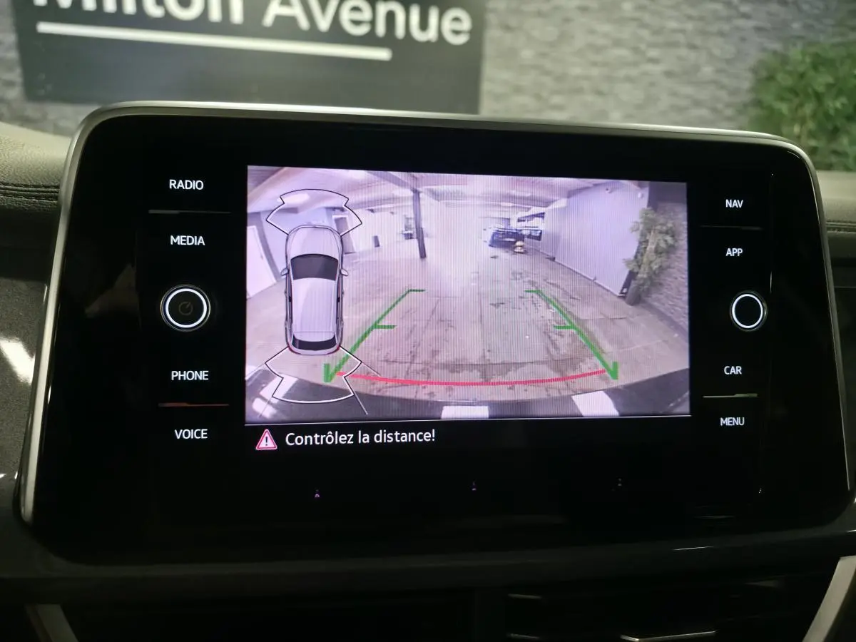 Écran tactile intérieur montrant la caméra de recul du Volkswagen T-Roc noir, avec lignes de guidage vertes et rouges.
