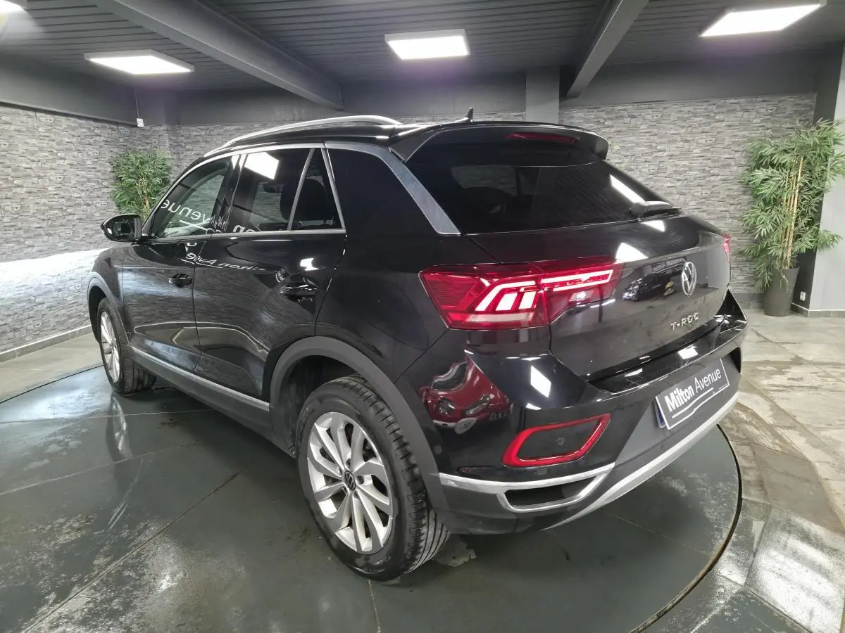 Vue 3/4 arrière droite du Volkswagen T-Roc noir 2022 avec feux LED et jantes alliage 17 pouces dans un showroom.