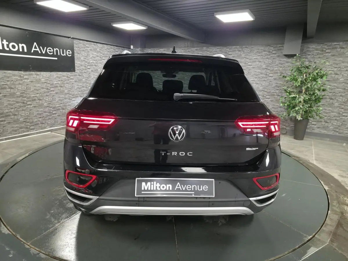 Vue arrière d'un Volkswagen T-Roc noir 2022 avec feux LED allumés dans un showroom intérieur.