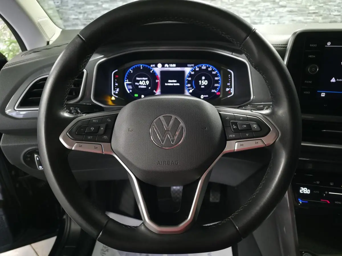 Vue rapprochée du volant en cuir noir multifonction du Volkswagen T-Roc 2022 avec tableau de bord digital lumineux.