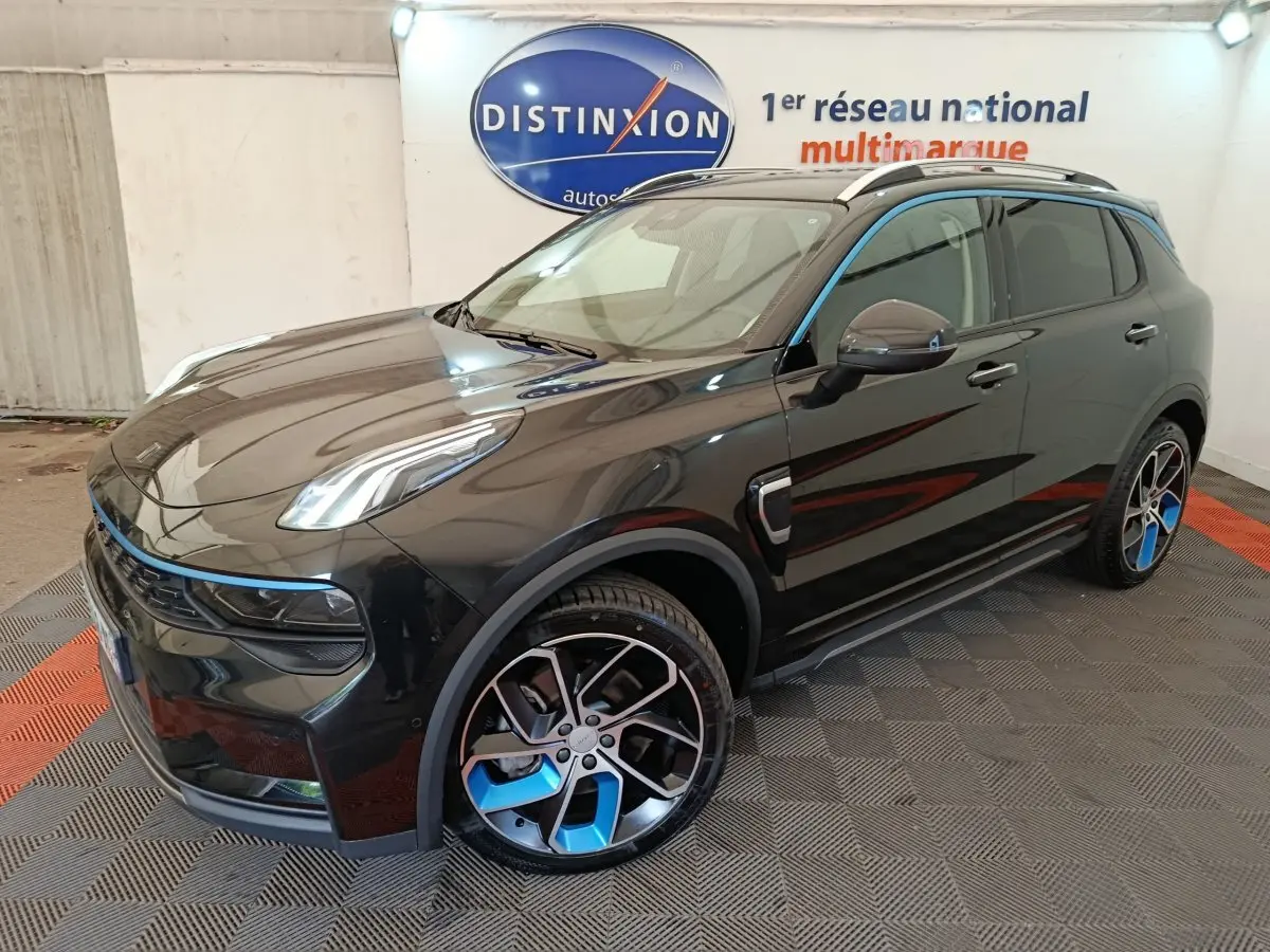 Vue 3/4 avant droite d'un SUV LINK & CO 01 noir avec jantes noires et bleues, dans un showroom intérieur.