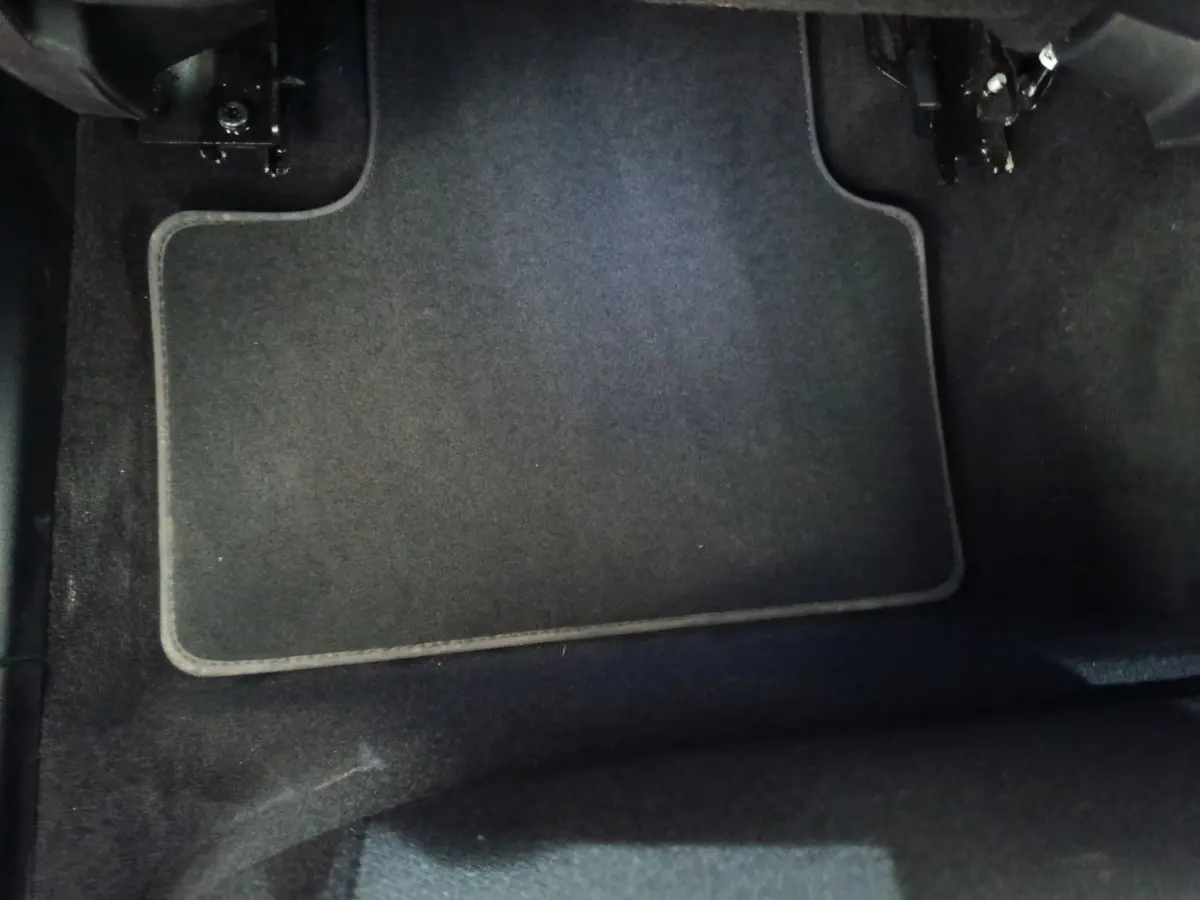 Tapis de sol noir dans l'habitacle du conducteur du SUV hybride rechargeable Link & Co 01, vue plongeante.