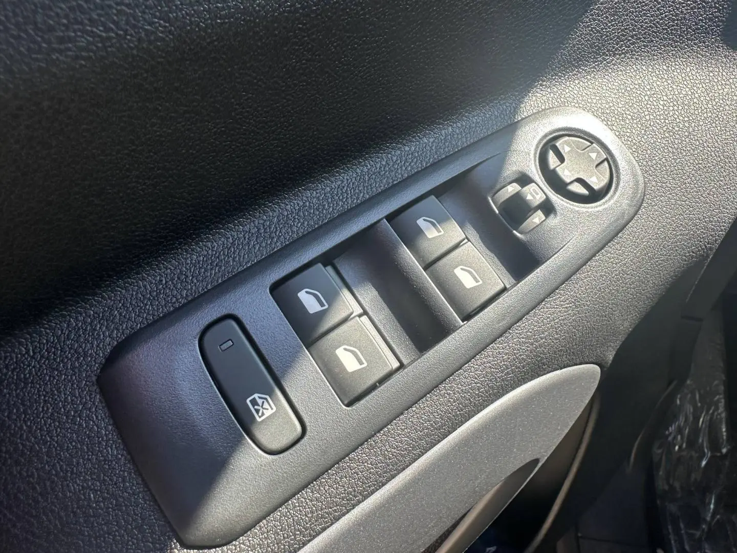 Gros plan sur les commandes des vitres électriques et rétroviseurs sur la porte avant gauche du Citroën Berlingo Sirkka Green.