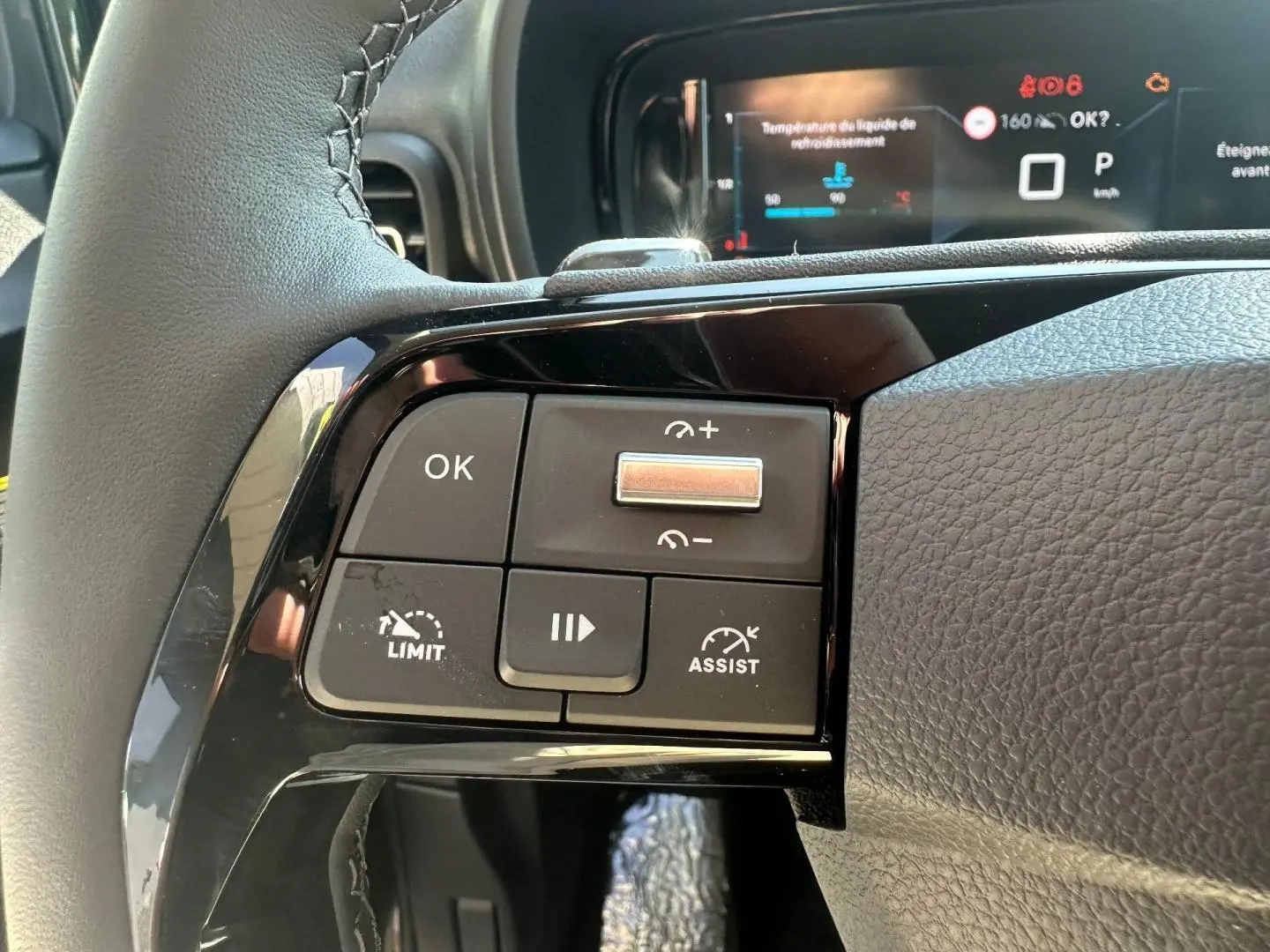 Gros plan sur les commandes multifonctions à gauche du volant cuir du Citroën Berlingo 2026, finition Urban Grey.