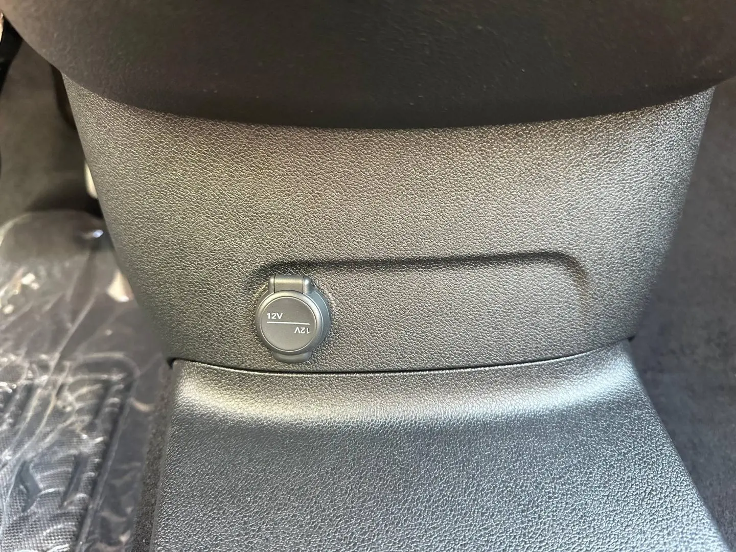 Prise 12V en gros plan sous la console centrale du CITROEN BERLINGO M 1.5 BlueHDi 130ch PLUS BVA8, intérieur noir.