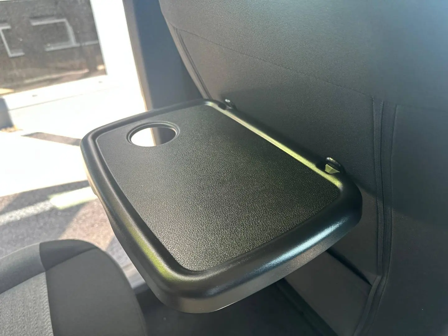 Tablette rabattable noire avec porte-gobelet, vue rapprochée sur le dossier d’un siège arrière du Citroën Berlingo 2026.