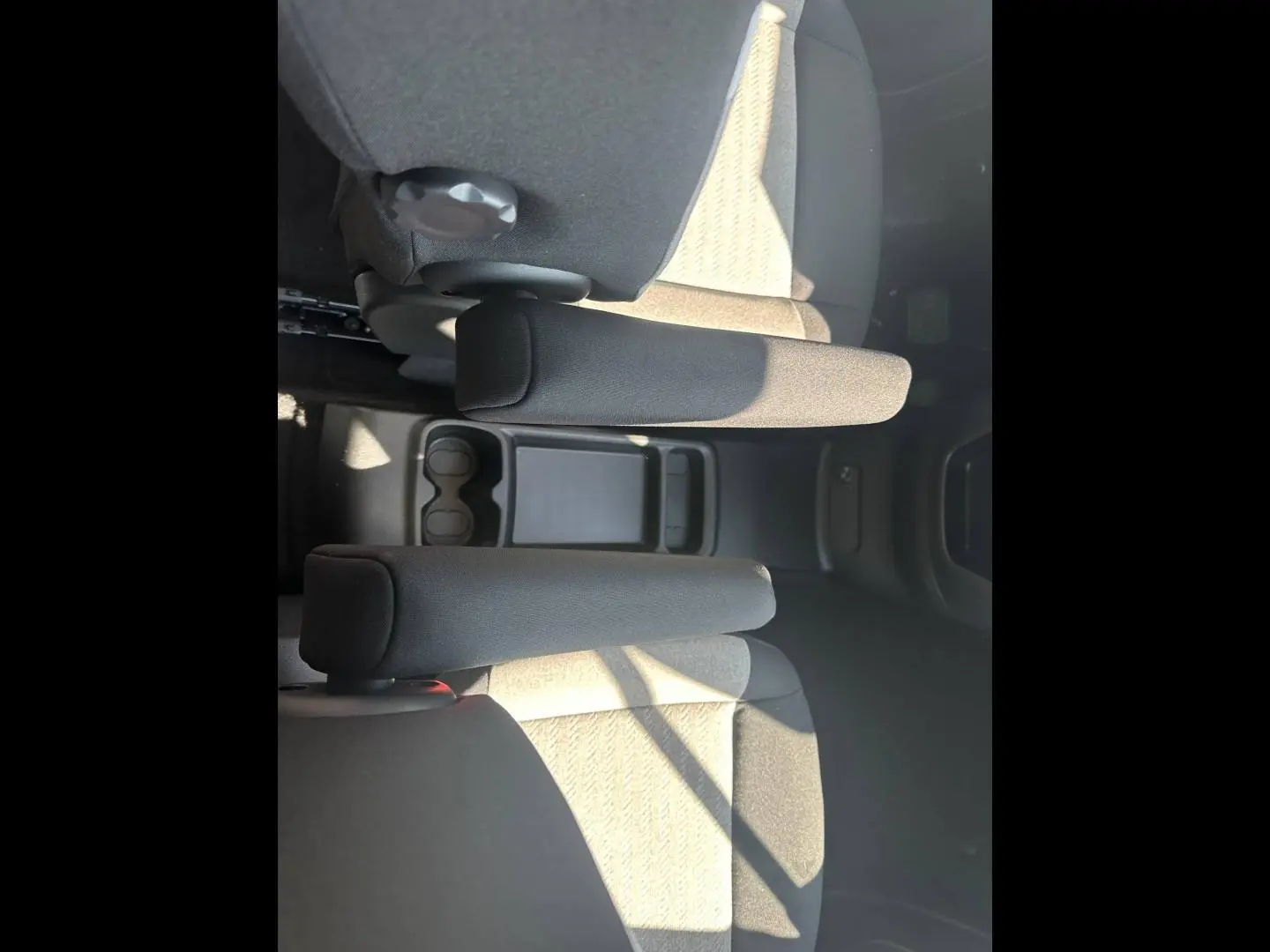 Vue plongeante sur les accoudoirs centraux et sièges arrière en tissu gris clair du Citroën Berlingo 2026.