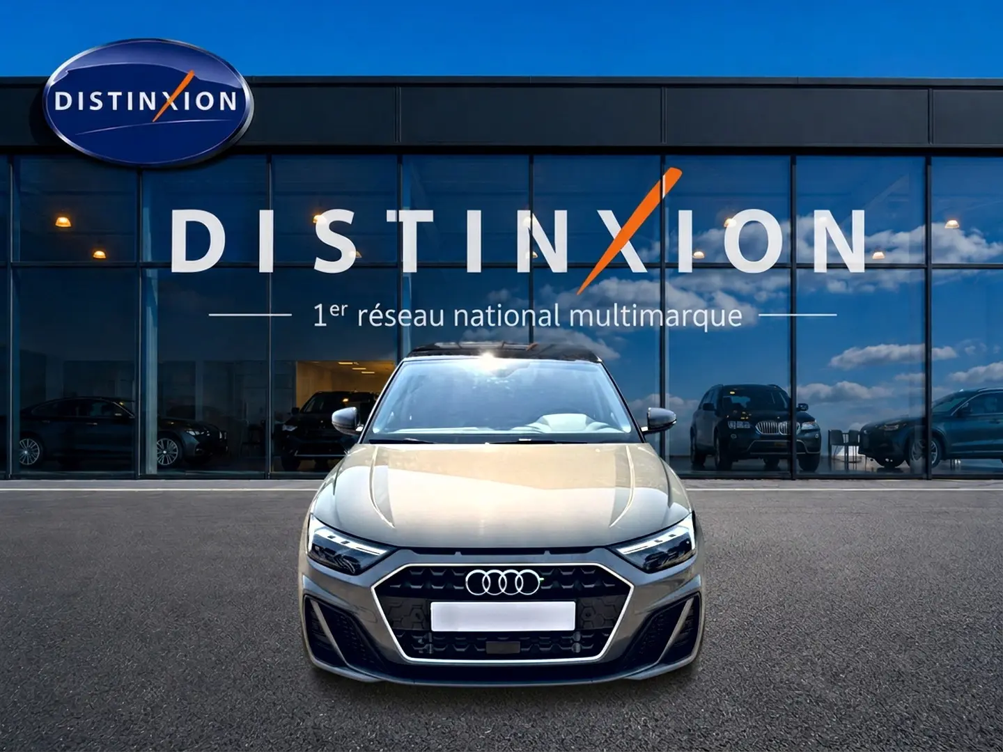 Vue de face d'une Audi A1 Sportback gris chronos avec toit noir, devant une vitrine Distinxion.