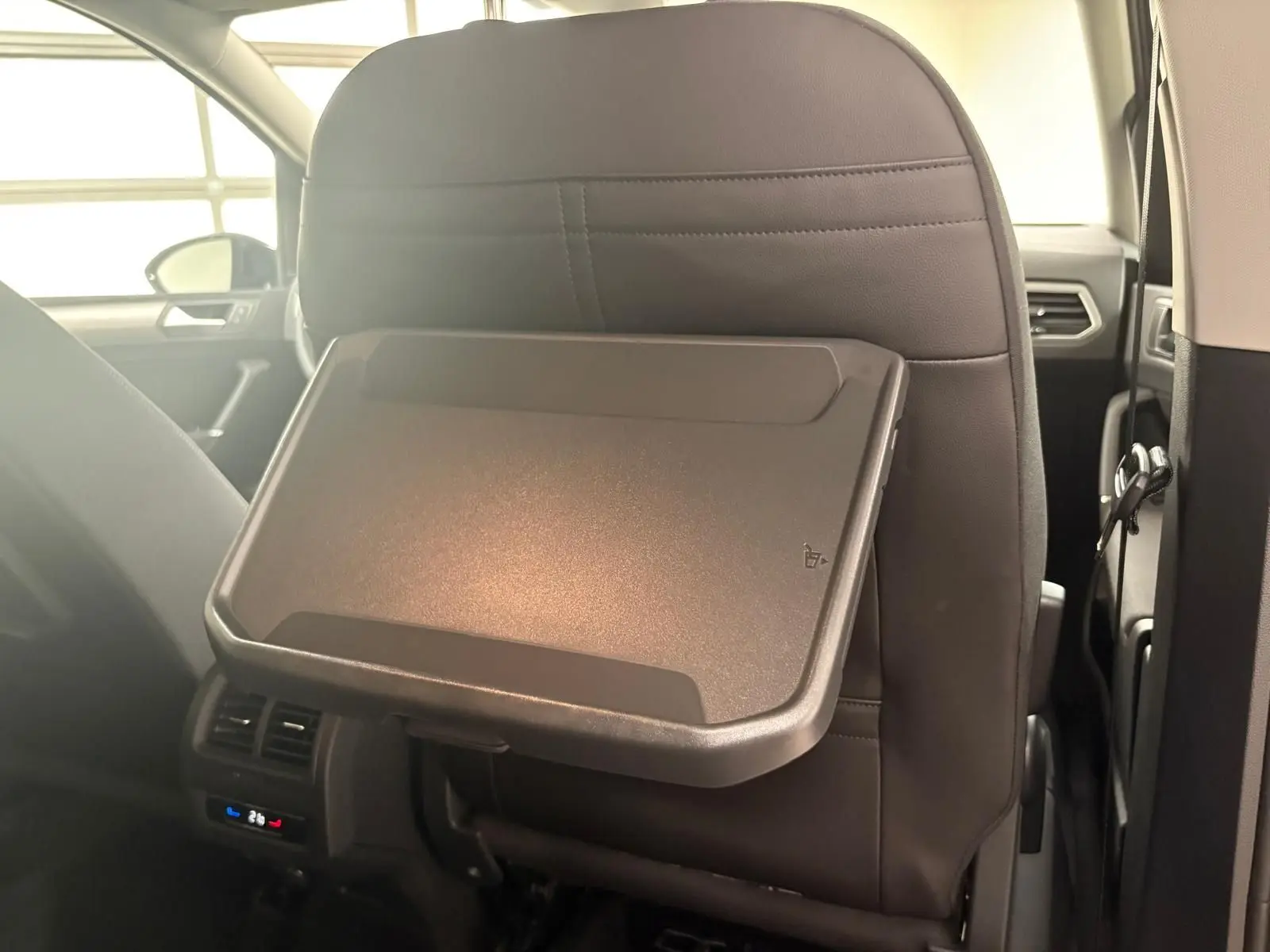 Tablette rabattable en plastique sur le dossier du siège avant noir dans l'habitacle du Volkswagen Touran gris Dauphin 2025.