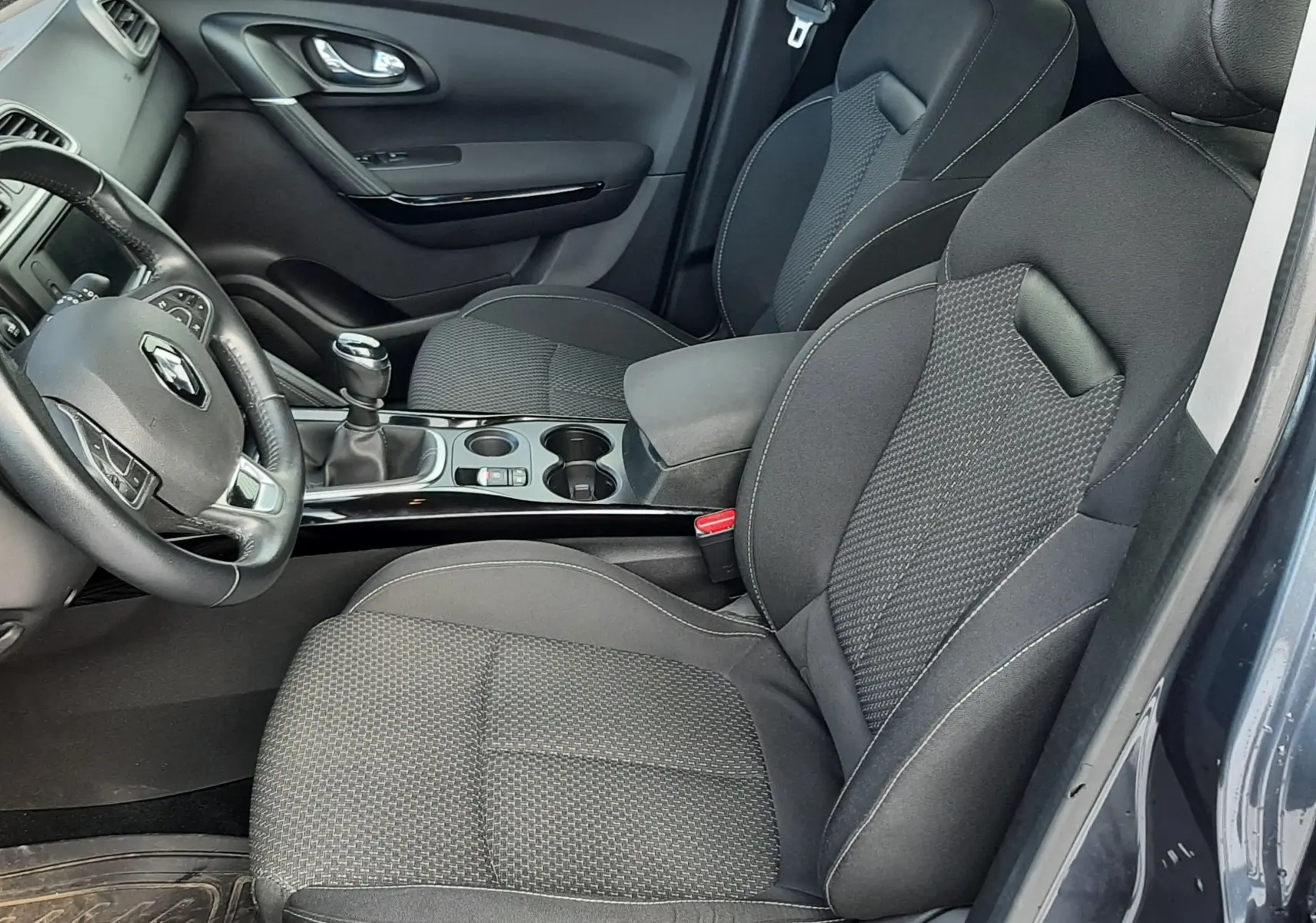 Intérieur côté conducteur du Renault Kadjar gris 2018, sièges tissu gris et levier de vitesse manuel visible.