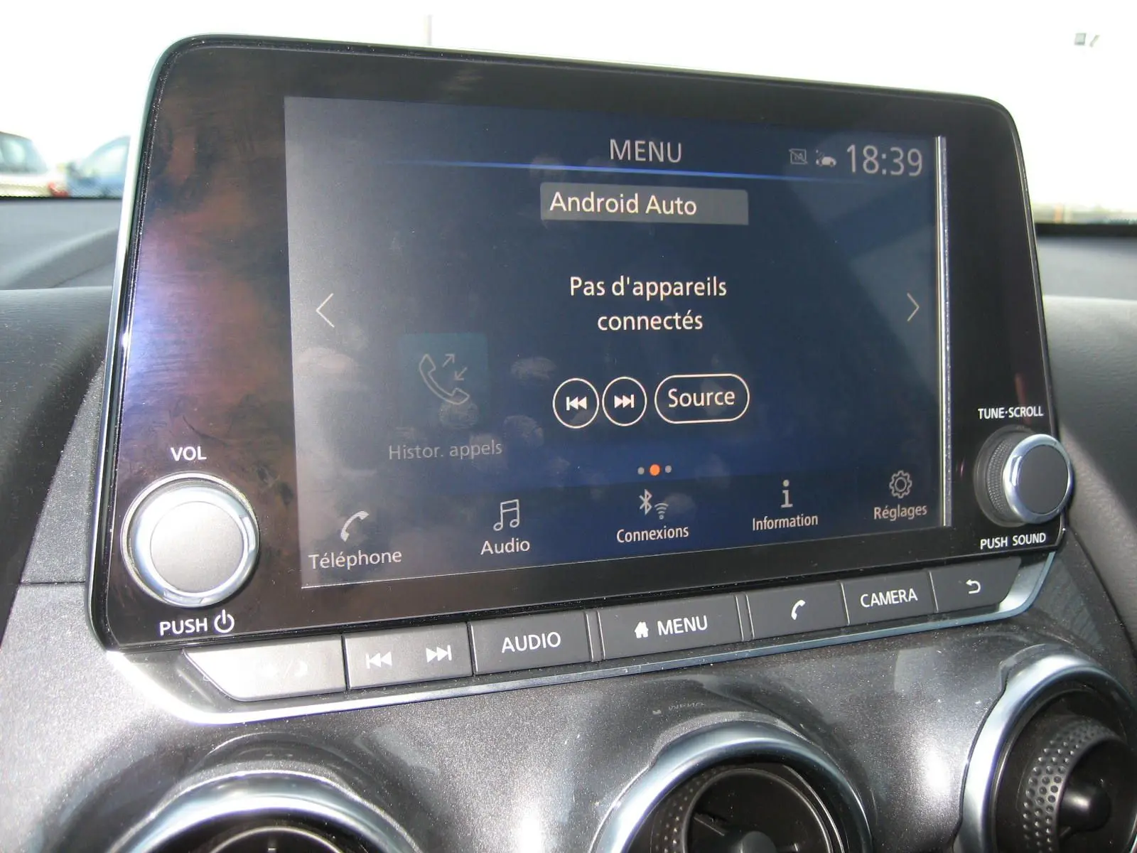 Vue rapprochée de l’écran tactile central du Nissan Juke 1.6 Hybrid 143 Tekna avec commandes audio et climatisation.