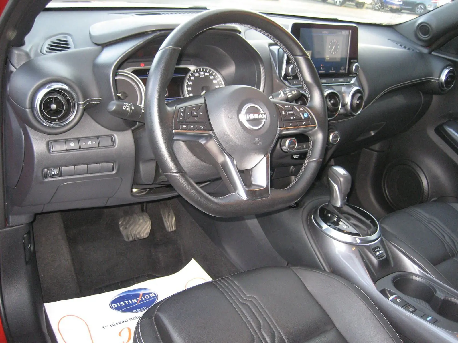 Vue intérieure côté conducteur du Nissan Juke 1.6 Hybrid 2024, avec volant cuir, tableau de bord numérique et console centrale moderne.