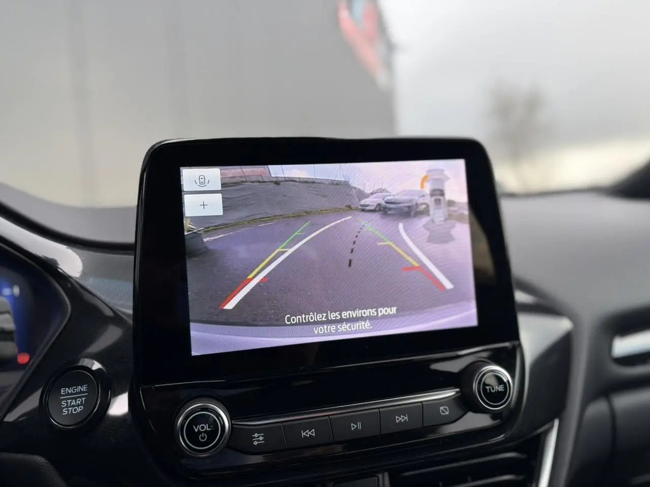 Écran tactile intérieur montrant la caméra de recul 180° du Ford Puma gris Solar, avec bouton démarrage et commandes audio.