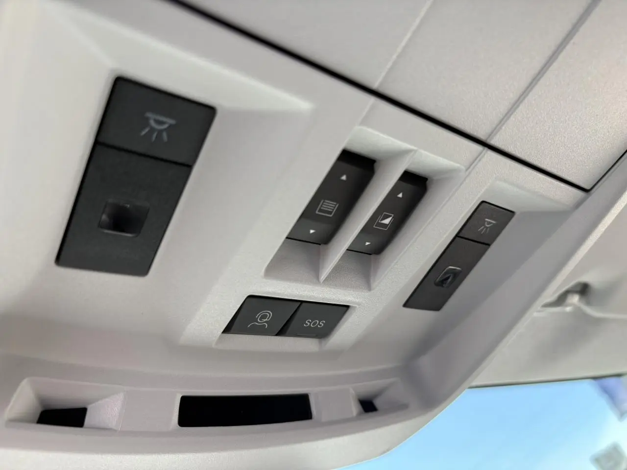 Vue en gros plan des commandes du toit ouvrant et des boutons SOS dans l'habitacle clair du Citroën C5 Aircross noir Perla.
