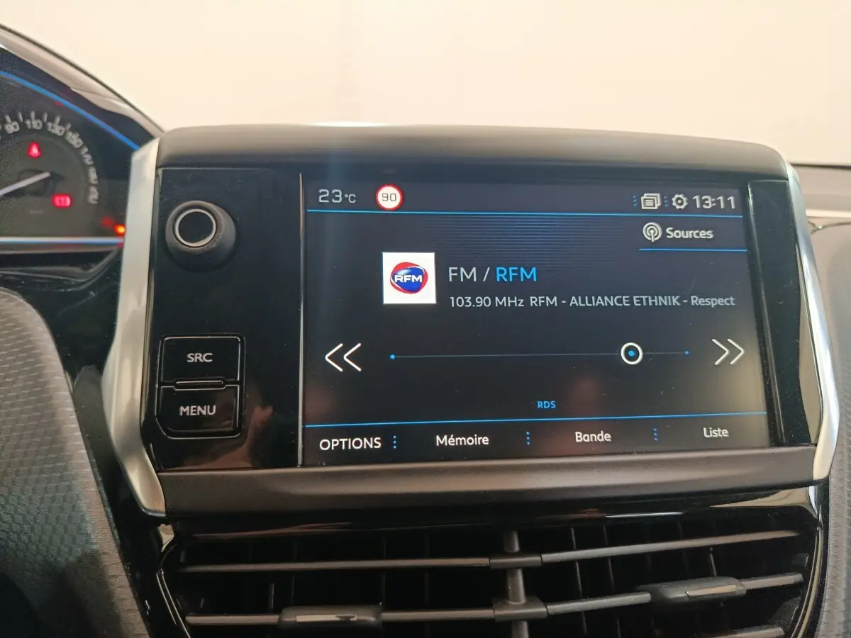 Écran tactile central de la Peugeot 2008 gris foncé affichant la radio FM avec commandes SRC et MENU visibles.