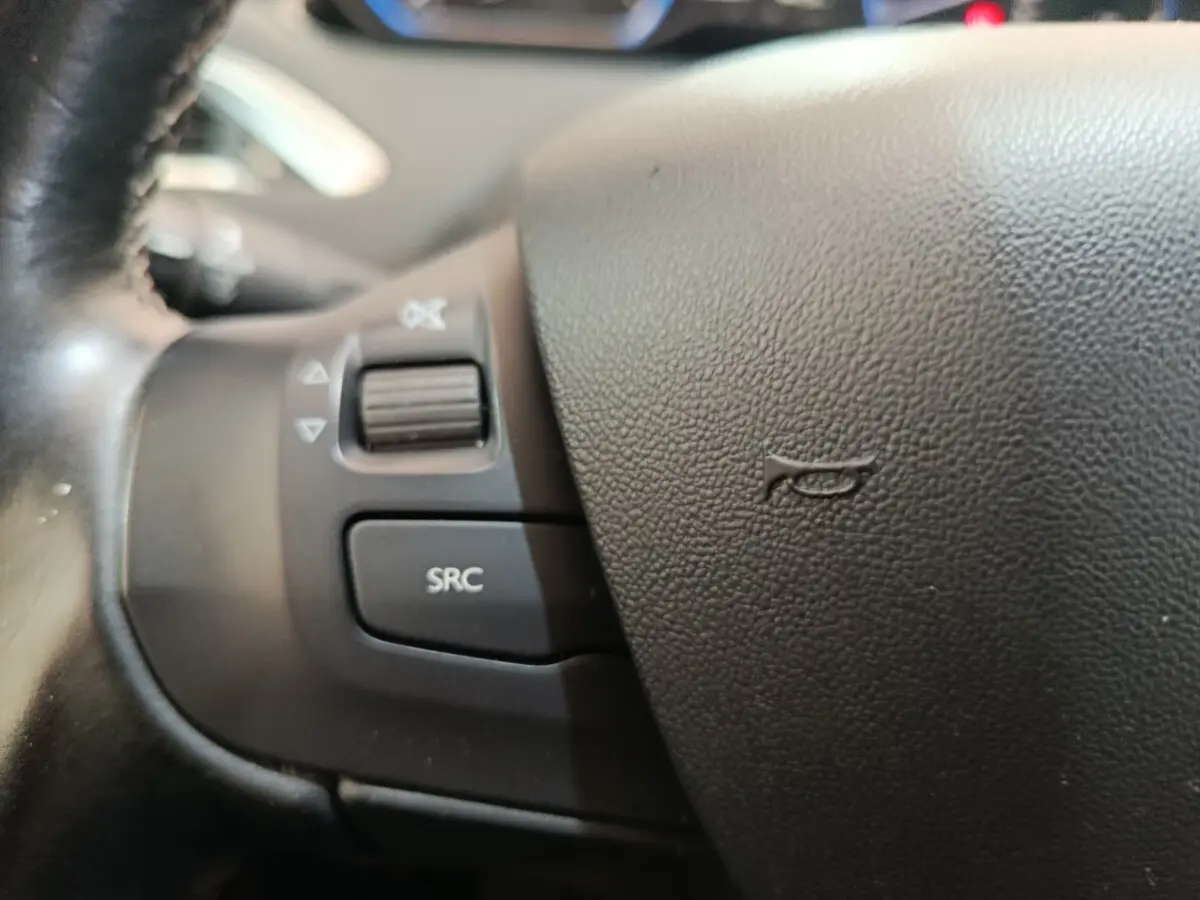Gros plan sur les commandes audio du volant cuir noir du Peugeot 2008 gris foncé, version Puretech 110 S&S EAT6 Allure.