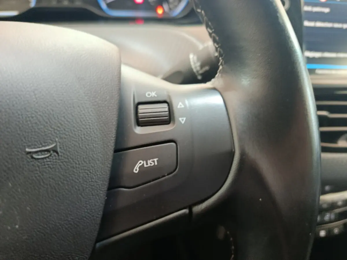 Gros plan sur le volant cuir noir de la Peugeot 2008 2019, avec commandes multifonctions visibles.