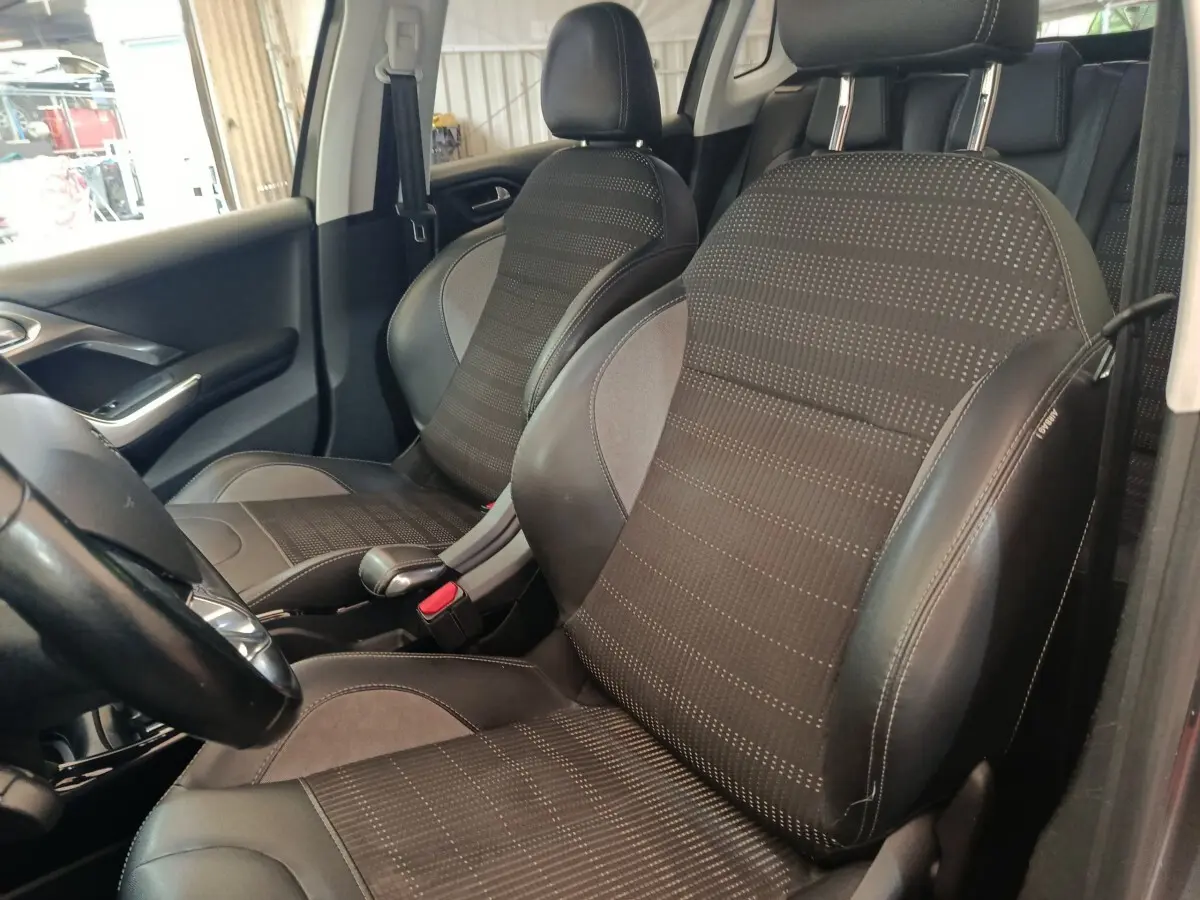 Vue intérieure côté gauche montrant les sièges avant en tissu et cuir noir du Peugeot 2008 gris foncé.