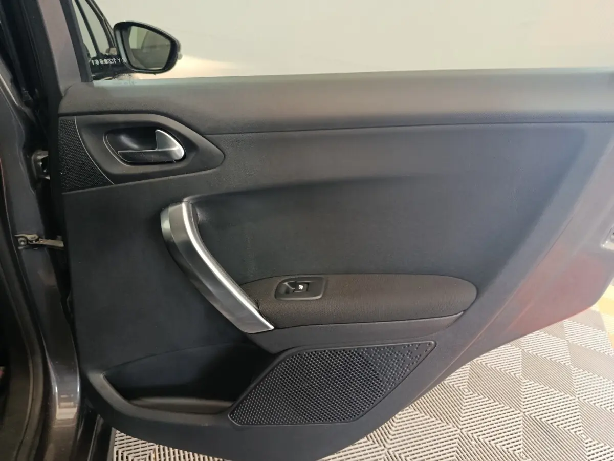 Vue intérieure côté gauche de la porte avant gris foncé du Peugeot 2008 avec poignée argentée et commande de vitre.