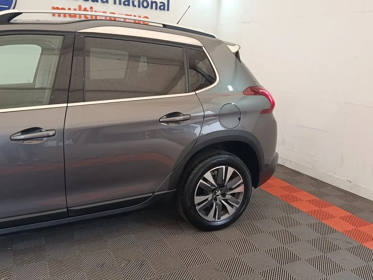 Vue côté droit arrière d’un Peugeot 2008 gris foncé avec jante alliage et vitres teintées.