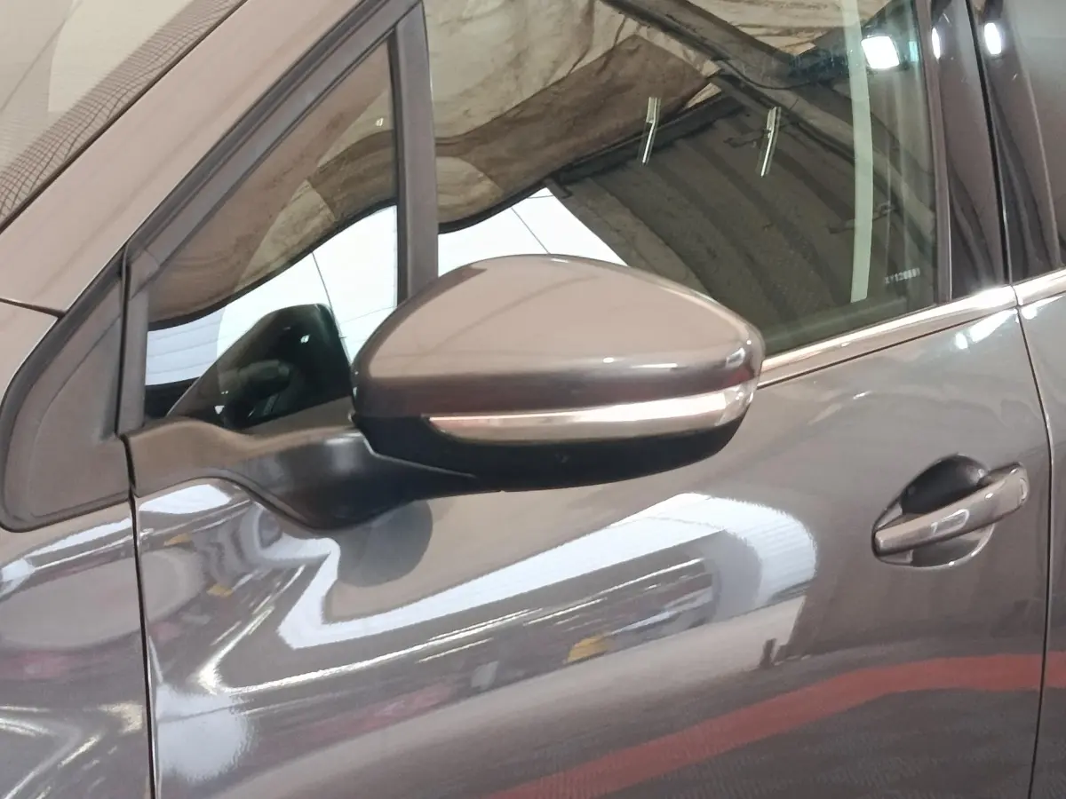 Gros plan sur le rétroviseur côté gauche et la portière gris foncé d'un Peugeot 2008 2019 stationné en intérieur.