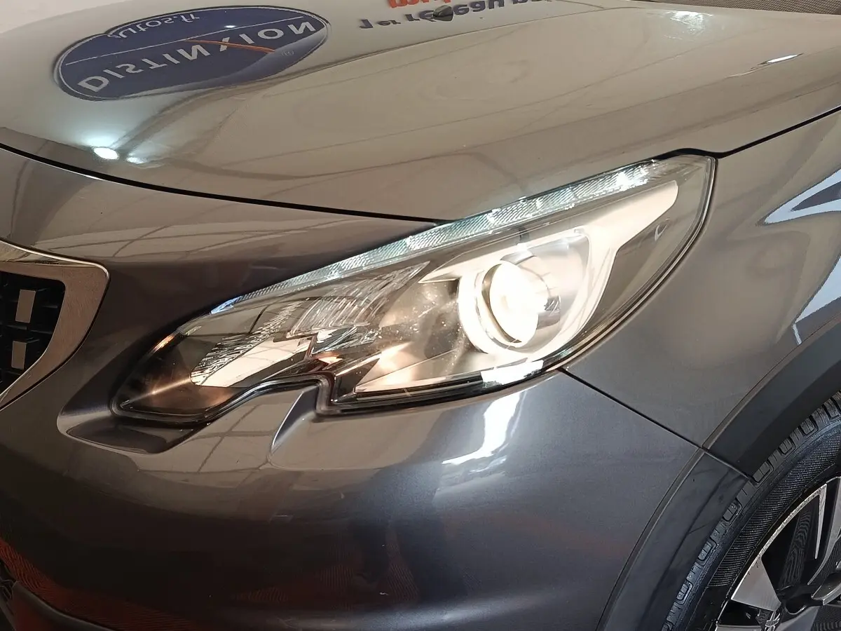 Gros plan sur le phare avant droit d’un Peugeot 2008 gris foncé, mettant en valeur les lignes modernes et le capot lisse.