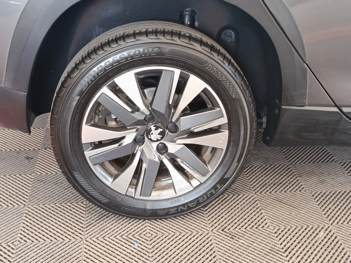 Gros plan sur la roue avant droite d’un Peugeot 2008 gris foncé, avec jante alliage et pneu Bridgestone.