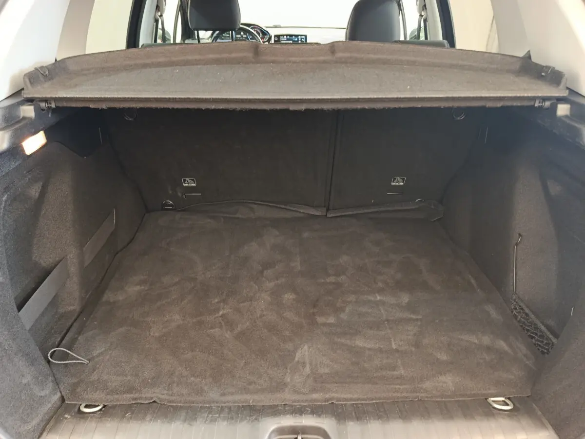Coffre spacieux et propre du Peugeot 2008 gris foncé, vue depuis l'arrière avec la tablette de coffre relevée.