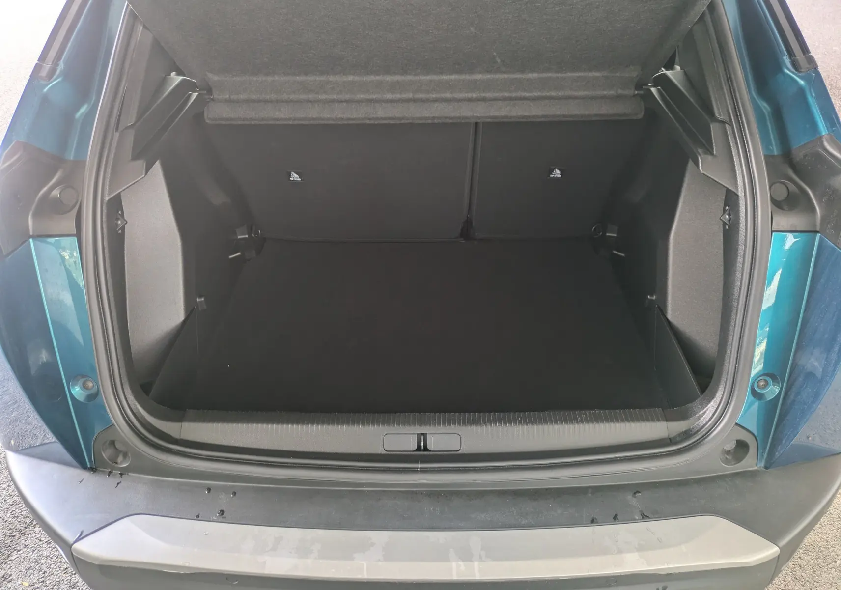 Coffre ouvert vu de l'arrière du Peugeot 2008 bleu obsession, montrant un espace de chargement vide et propre.