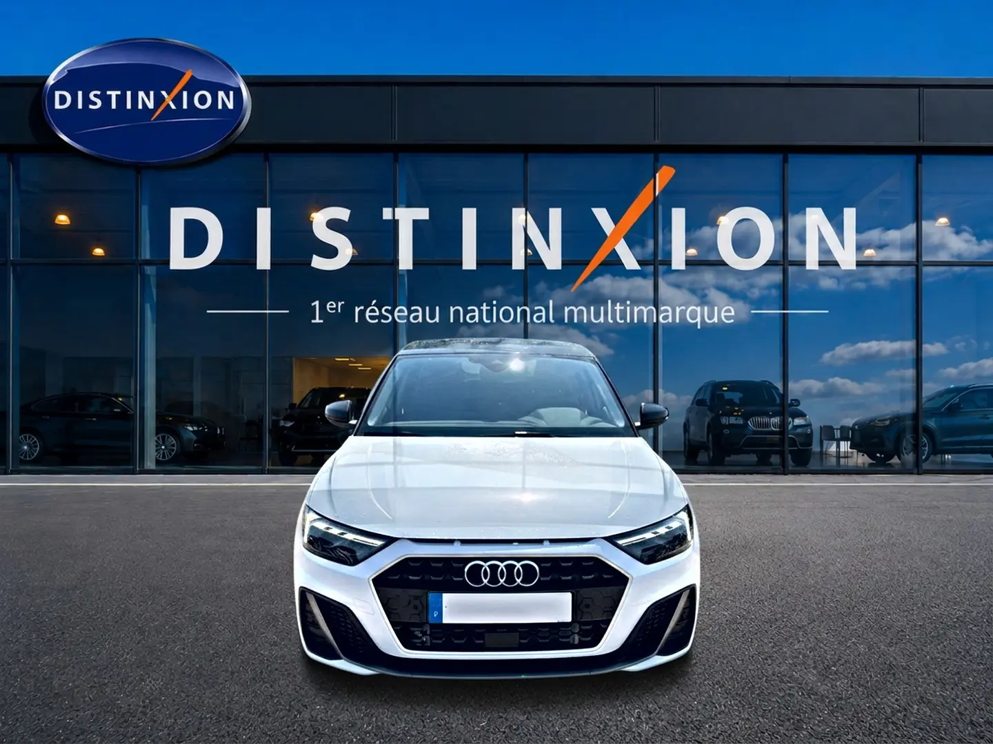 Audi A1 Sportback blanc et noir vue de face, avec calandre noire et logo Audi visible devant un showroom Distinxion.