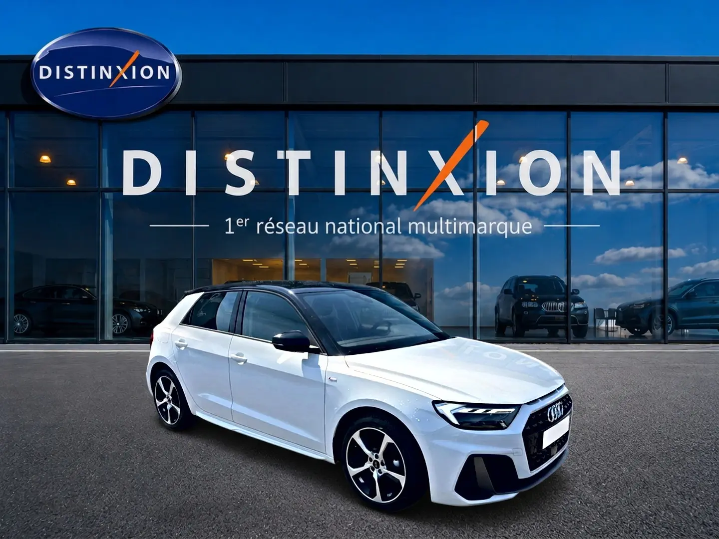Audi A1 Sportback blanc et noir en vue 3/4 avant droit, avec jantes alu et toit noir brillant devant un showroom Distinxion.