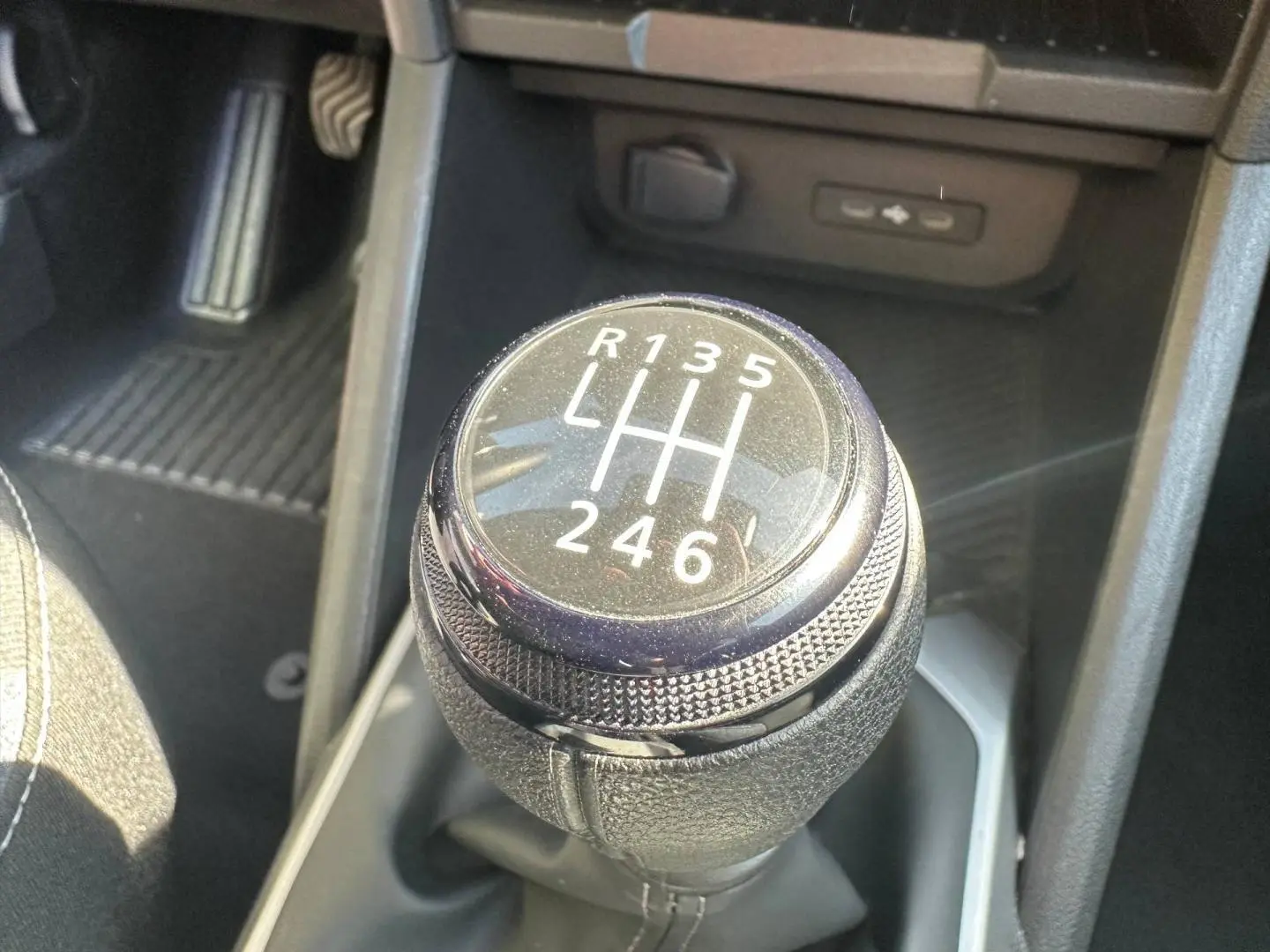 Gros plan sur le levier de vitesses manuel noir du Dacia Duster 1.2 mild hybrid 130ch en intérieur.