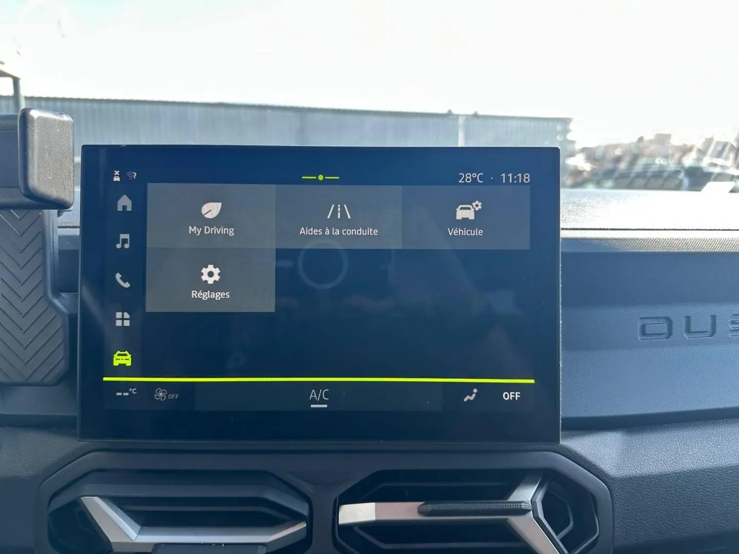 Vue rapprochée de l’écran tactile central du Dacia Duster 2025, affichant les aides à la conduite, avec tableau de bord noir.