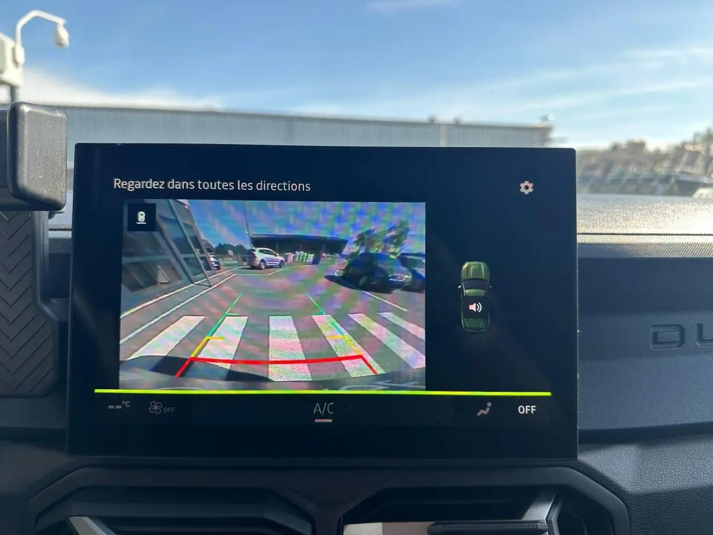 Écran tactile intérieur montrant la caméra de recul du Dacia Duster 2025 couleur Sandstone en stationnement.
